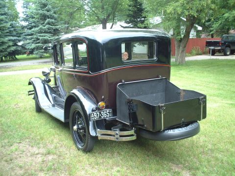 1929 Ford Model A - A 1929 Ford Model A sedan with a rear trunk sits on a grassy lawn.