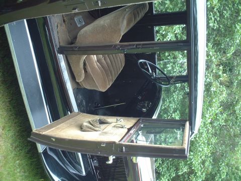 1929 Ford Model A - The interior of a classic car shows its aged seats, door panels, and steering wheel.