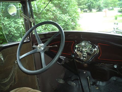 1929 Ford Model A - The dashboard of a vintage car features a central instrument cluster with multiple gauges and a large steering wheel.