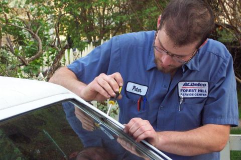 1985 Ford Crown Victoria LTD - Mechanic working on the window trim of a vehicle.