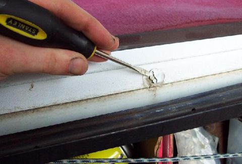 1985 Ford Crown Victoria LTD - A hand uses a Stanley tool to scrape damaged white trim near a red surface.
