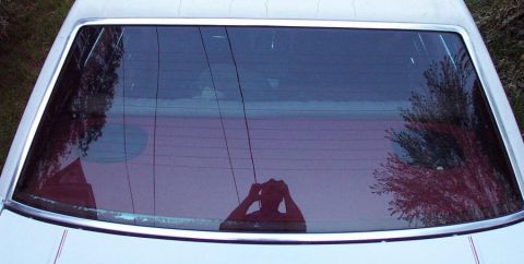 1985 Ford Crown Victoria LTD - View of the rear window and its chrome trim, with reflections of the surroundings.