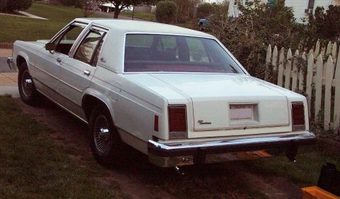 1985 Ford Crown Victoria LTD - This 1985 Ford Crown Victoria LTD is shown from the rear, parked on a slight incline beside a fence.