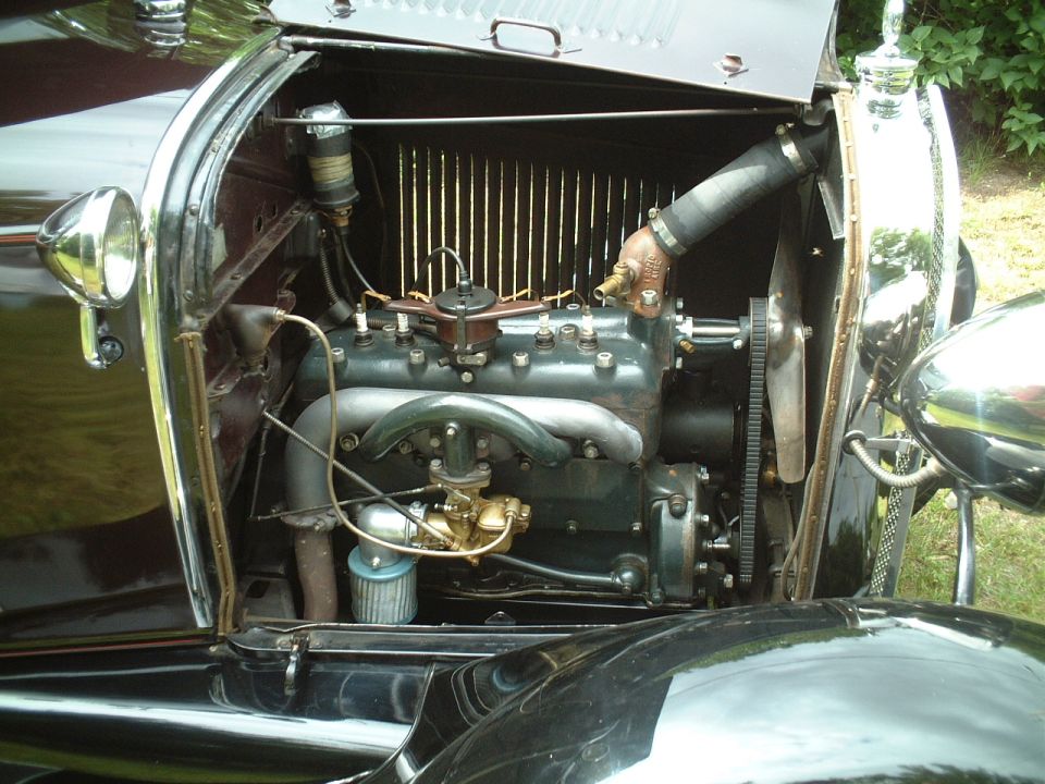 Prewar Ford four-cylinder engine bay with brass carburetor and open side hood panel
