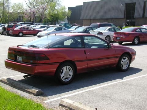 1991 Ford Probe - A red 1991 Ford Probe is parked in a lot with other vehicles.
