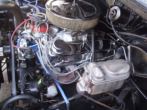 1985 Ford Bronco - Driver-side engine bay view of a V8 with a chrome Edelbrock air cleaner, chrome valve cover with breather, red distributor cap and blue spa…