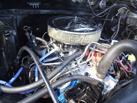 1985 Ford Bronco - Engine bay shot of a V8 wearing a chrome-lid Edelbrock round air cleaner with white gauze element on top of a four-barrel carburetor. Blue…