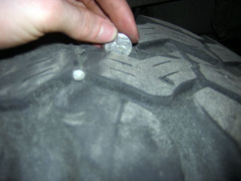 1995 Ford Bronco - A hand inserts a coin into a tire's tread, possibly to check for damage.