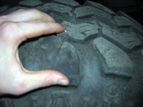 1995 Ford Bronco - A hand is shown pressing down on the tread of a tire, highlighting its depth and pattern.