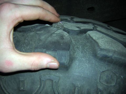 1995 Ford Bronco - A coin is being pressed into the tread of a tire.