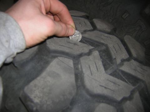 1995 Ford Bronco - A quarter is used to gauge the remaining tread depth on a vehicle's tire.
