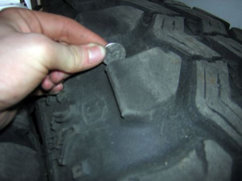 1995 Ford Bronco - Checking tire tread depth with a coin on a large off-road tire.