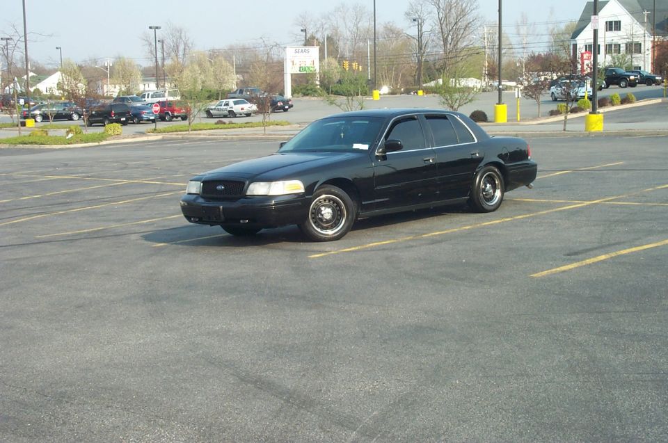 Black Ford Crown Victoria parked at angle in empty shopping center lot, driver's side view
