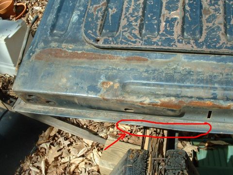 1985 Ford Bronco - This image shows a close-up of a heavily rusted tailgate, with a red circle and arrow pointing to a specific area of damage.