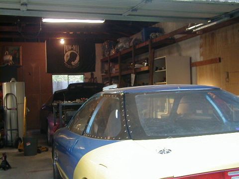 1993 Ford Probe - Two vehicles are parked inside a garage, one with its hood open and the other partially visible in the foreground.