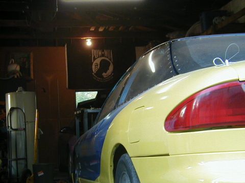 1993 Ford Probe - A car with two-tone paint is parked inside a garage, with a POW-MIA flag hanging in the background.