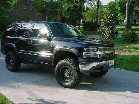2000 Chevrolet Tahoe - A black Chevrolet Tahoe is parked on a concrete driveway in front of a wooded area.