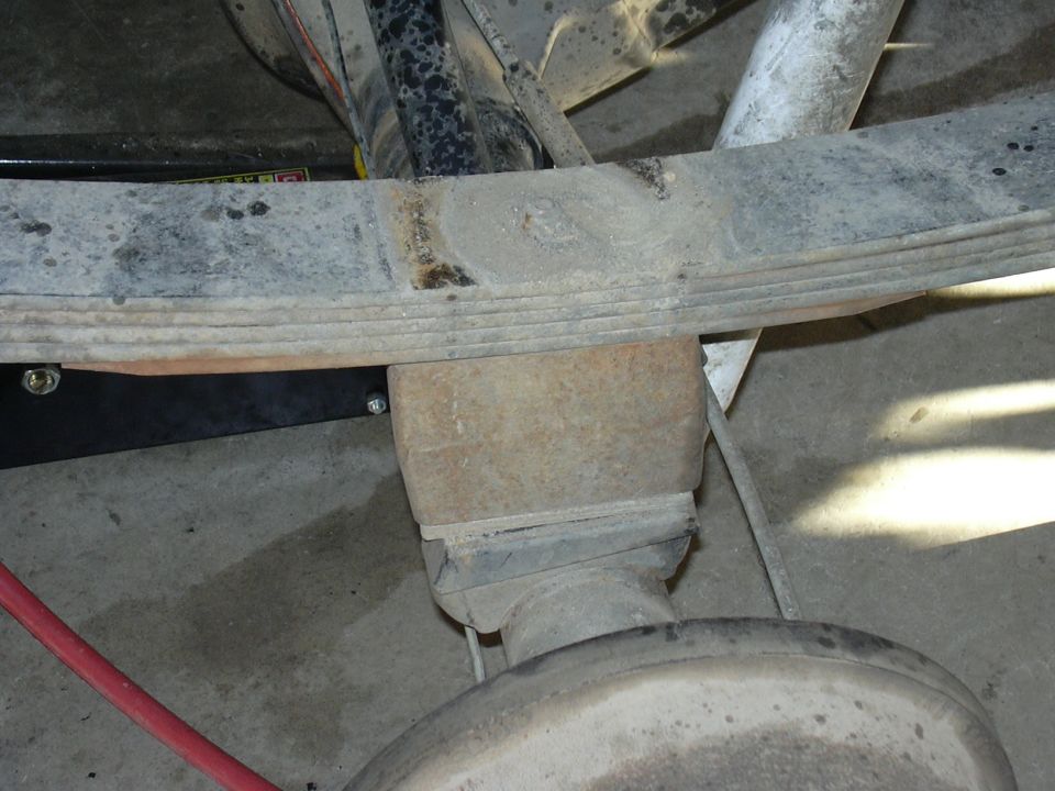 Close view of a leaf spring pack mounted over a rear axle differential in a garage