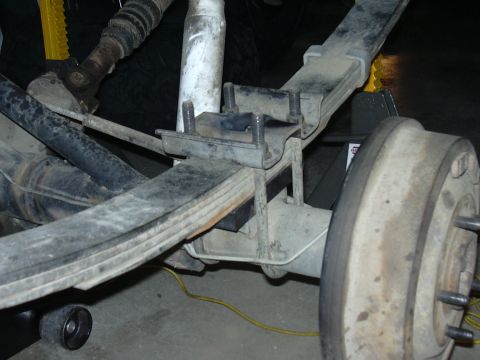 1991 Ford Bronco - Close-up of a rear leaf spring suspension and axle assembly viewed from below/behind, showing a new U-bolt spring plate with exposed bolt t…