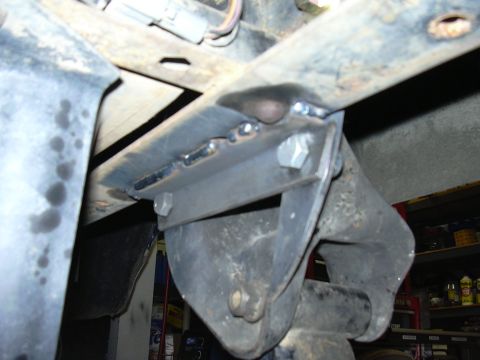 1991 Ford Bronco - Underside view of a fabricated steel bracket or mount welded to a vehicle frame crossmember, showing fresh weld beads and a large hex bolt.…