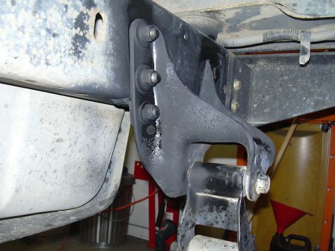 1991 Ford Bronco - Close-up underside view of a freshly painted gray steel frame bracket bolted to the frame rail with three vertical hex bolts, mounting a bl…
