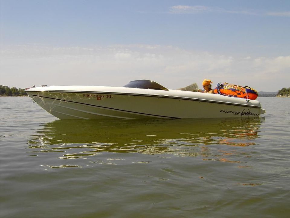 White speedboat on calm water, side view, with orange tube in cockpit