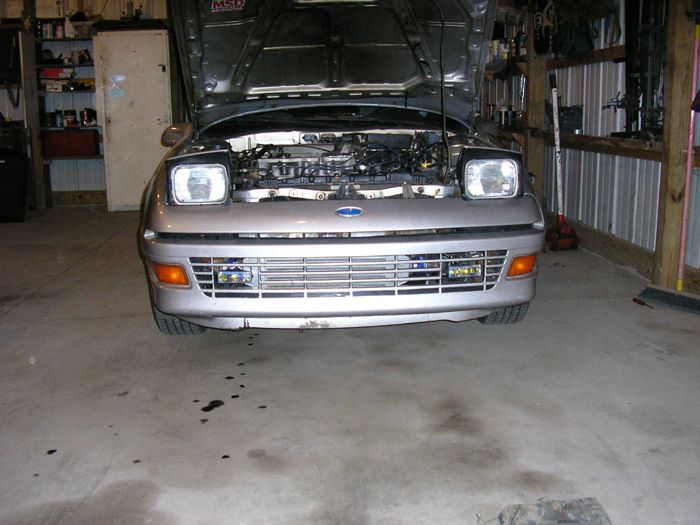 Silver 1990 Ford Probe with hood open, front view, showing engine and grille