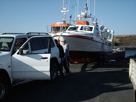 1996 Ford Bronco - A white SUV is parked near a boat being prepared for launch or retrieval.