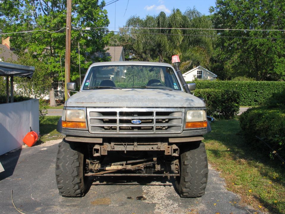 Front view of a lifted gray Ford 4x4 truck showing exposed front axle and mud tires