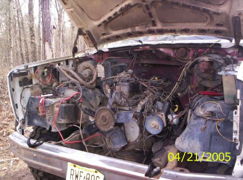 1985 Ford Bronco - The engine bay of a 1985 Ford Bronco is exposed, revealing its mechanical components and wiring harness.
