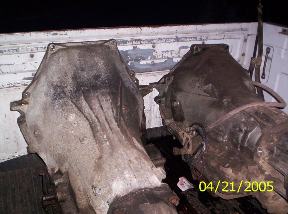 Two dirty transmission assemblies in the bed of a pickup truck