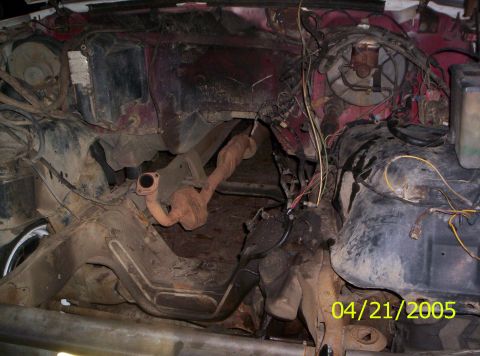 1985 Ford Bronco - The engine bay of a vehicle is shown, with visible exhaust components and wiring harnesses.