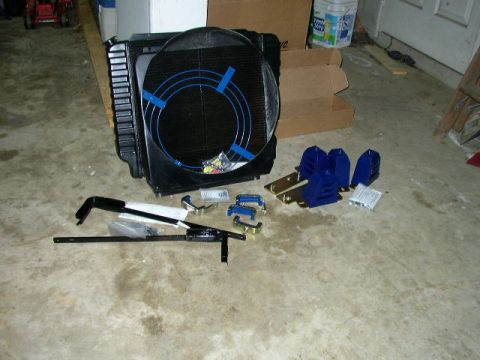 1995 Ford Bronco - A radiator and fan assembly, along with various mounting hardware, are laid out on a concrete surface.