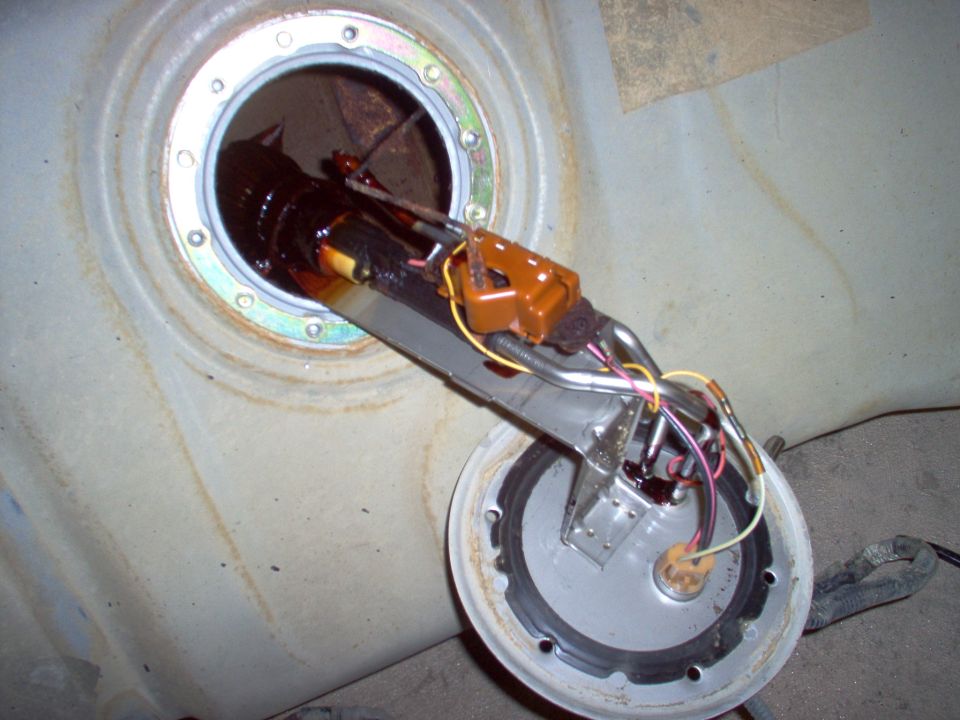 Fuel pump sending unit assembly pulled partway from a rusty fuel tank opening