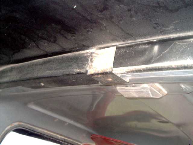 Interior roofline of a Bronco showing taped weatherstrip seal at windshield header near dome light