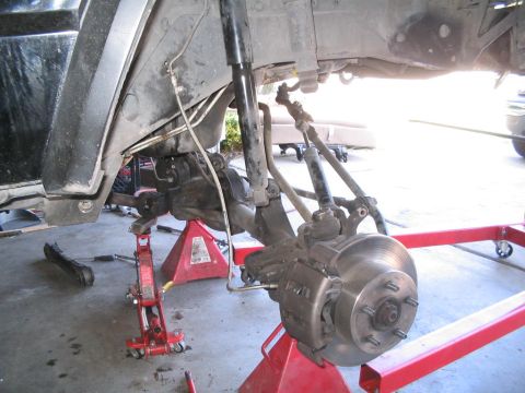 1994 Jeep Cherokee - The front suspension and brake components of a vehicle are shown while it is elevated on jack stands for maintenance.
