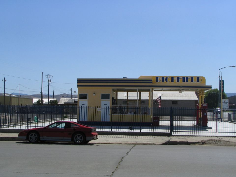 Red sports car parked by a vintage Richfield gas station