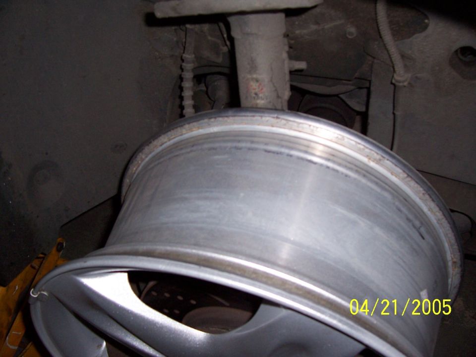 Close-up of a car's alloy wheel and part of the suspension system. Date stamp reads 04/21/2005