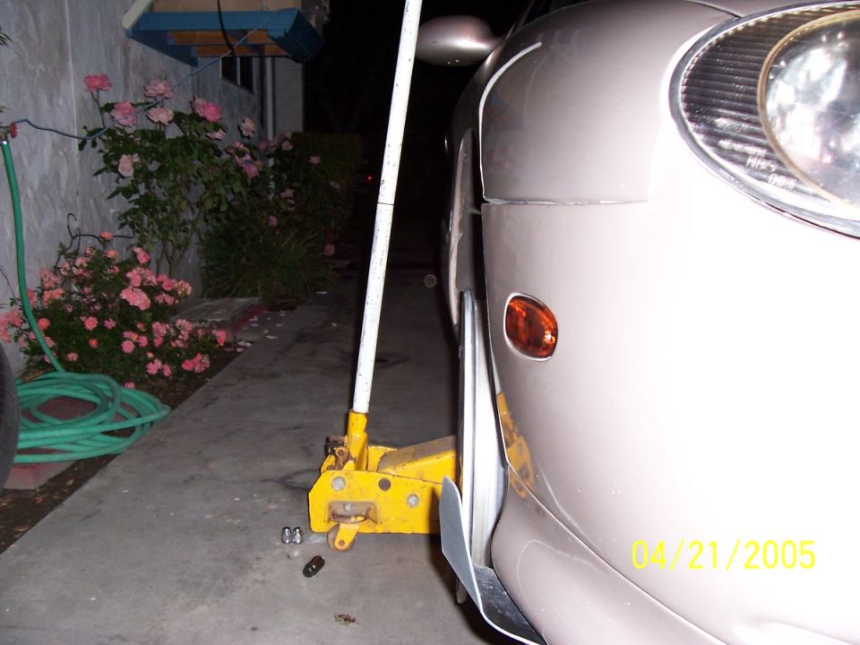 Car jack lifting the front fender of a light-colored car. Date stamp reads 04/21/2005