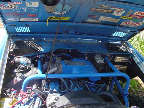 1971 Ford Bronco - The open hood reveals a custom blue engine bay with a roll cage and numerous stickers adorning the underside of the hood.