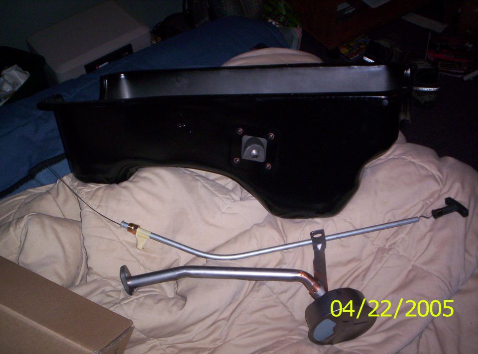 Black oil pan with dipstick assembly on a blanket. Date stamp reads 04/22/2005