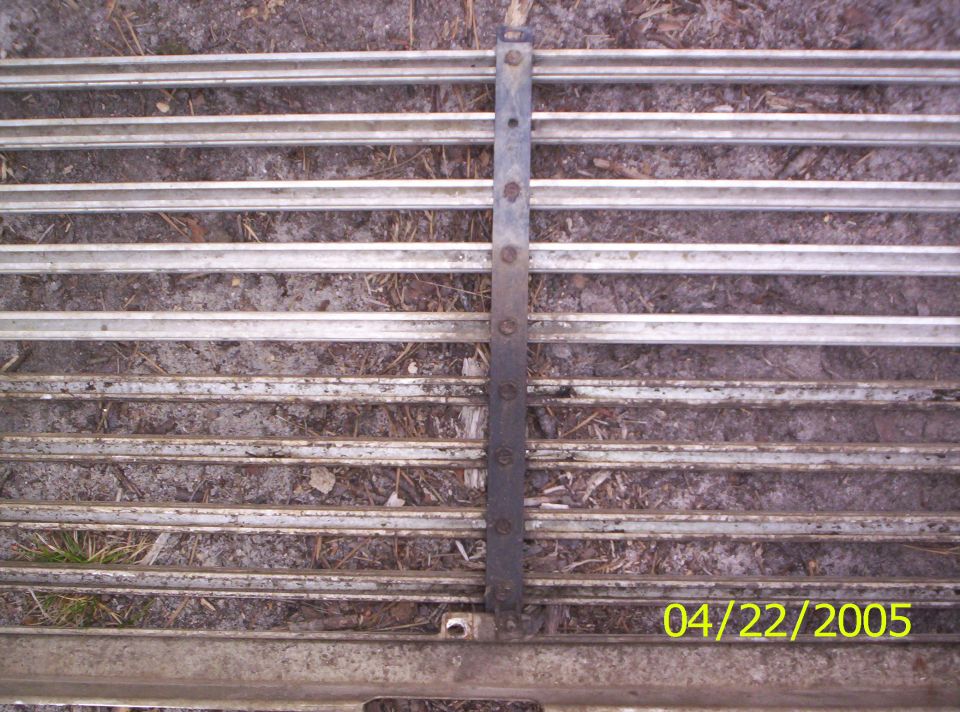 Close-up of a horizontal metal grille with a vertical support strip