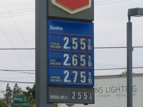 1990 Ford Bronco - blue gas station price sign listing regular unleaded at 2.55, plus 2.65, supreme 2.75, and diesel no.2 at 2.55.