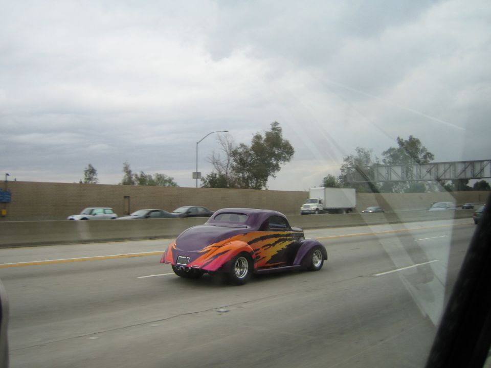 Purple flame-painted hot rod coupe driving on a freeway
