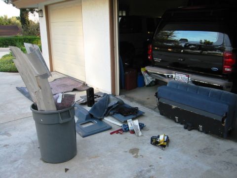 1985 Ford Bronco - Disassembled car parts and a black SUV are visible in a garage setting.