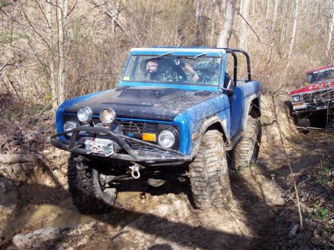 1974 Ford Bronco - This blue 1974 Ford Bronco is equipped for adventure, tackling a challenging muddy course with its winch and tires.