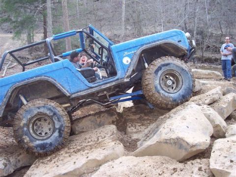 1974 Ford Bronco - A blue 1974 Ford Bronco navigates a challenging rocky terrain, demonstrating its off-road capabilities.