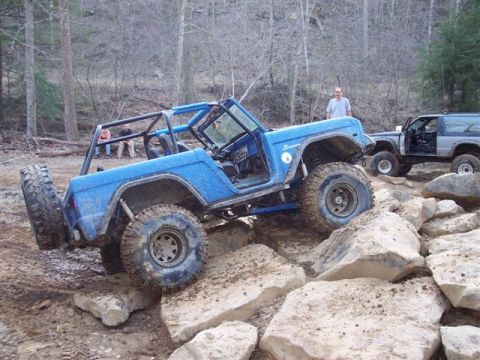 1974 Ford Bronco - A blue 1974 Ford Bronco tackles a rocky trail, with another SUV visible in the background.