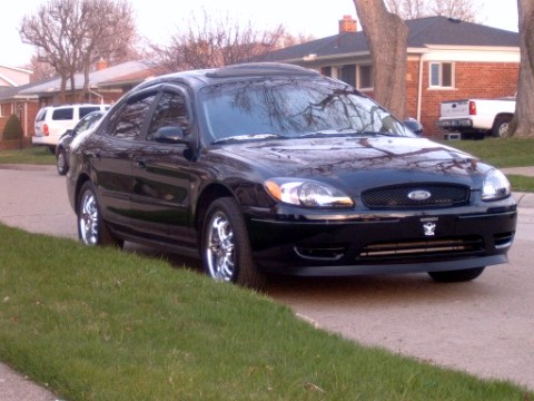2004 Ford Taurus - Front 3/4 view of a black 2004 Ford Taurus sedan parked on the side of a street.
