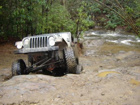 1989 Ford Bronco - This Jeep Wrangler is tackling a challenging off-road course with a river nearby.